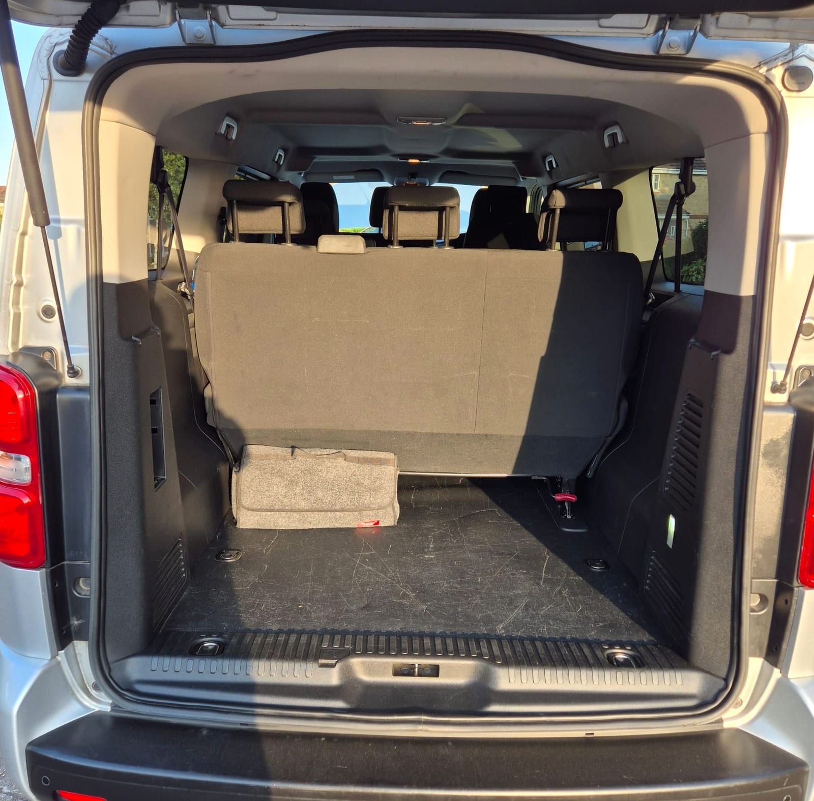 The back of a minibus with the tailgate up and the rear seats folded away for load space.